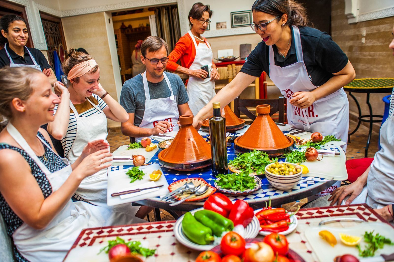 A group of people participating in a cooking class in Marrakech, Morocco. The chef is explaining is to the participants how to prepare the food.